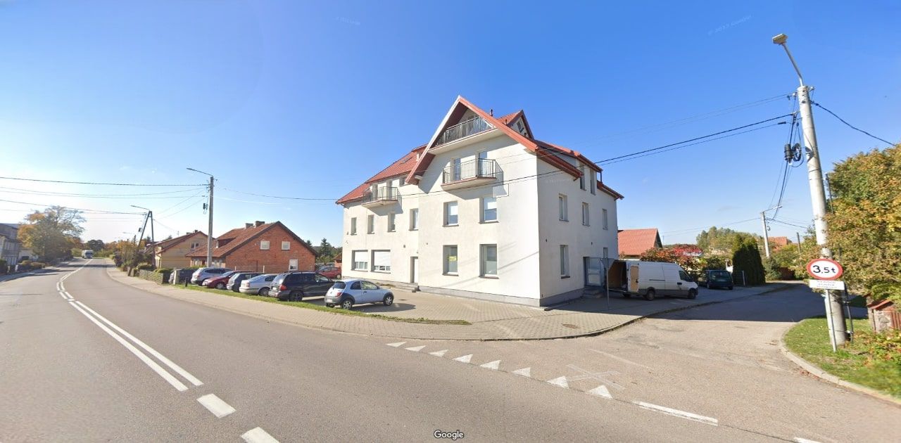 Eckansicht eines Wohngebäudes mit rotem Dach und heller Fassade – Straßenperspektive