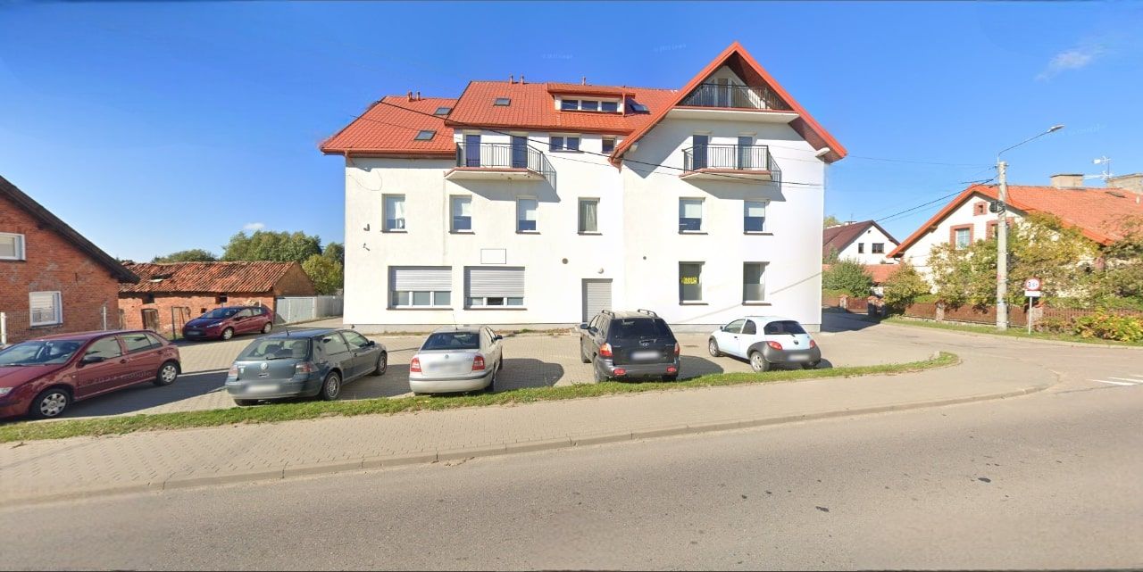 Foto der Fassade eines Wohngebäudes mit rotem Dach, weißem Putz und Balkonen